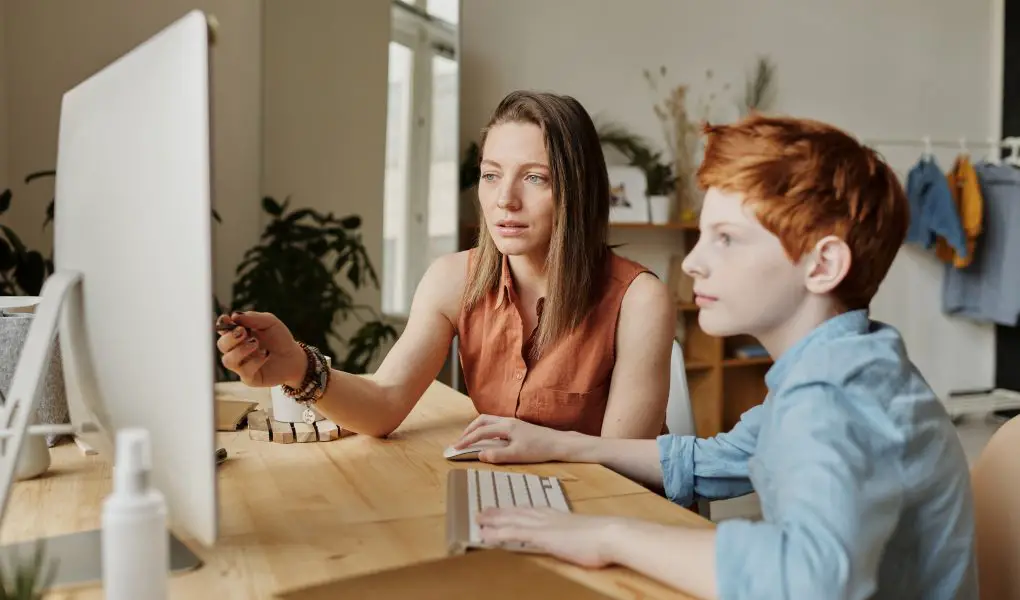 Photo of woman tutoring young boy